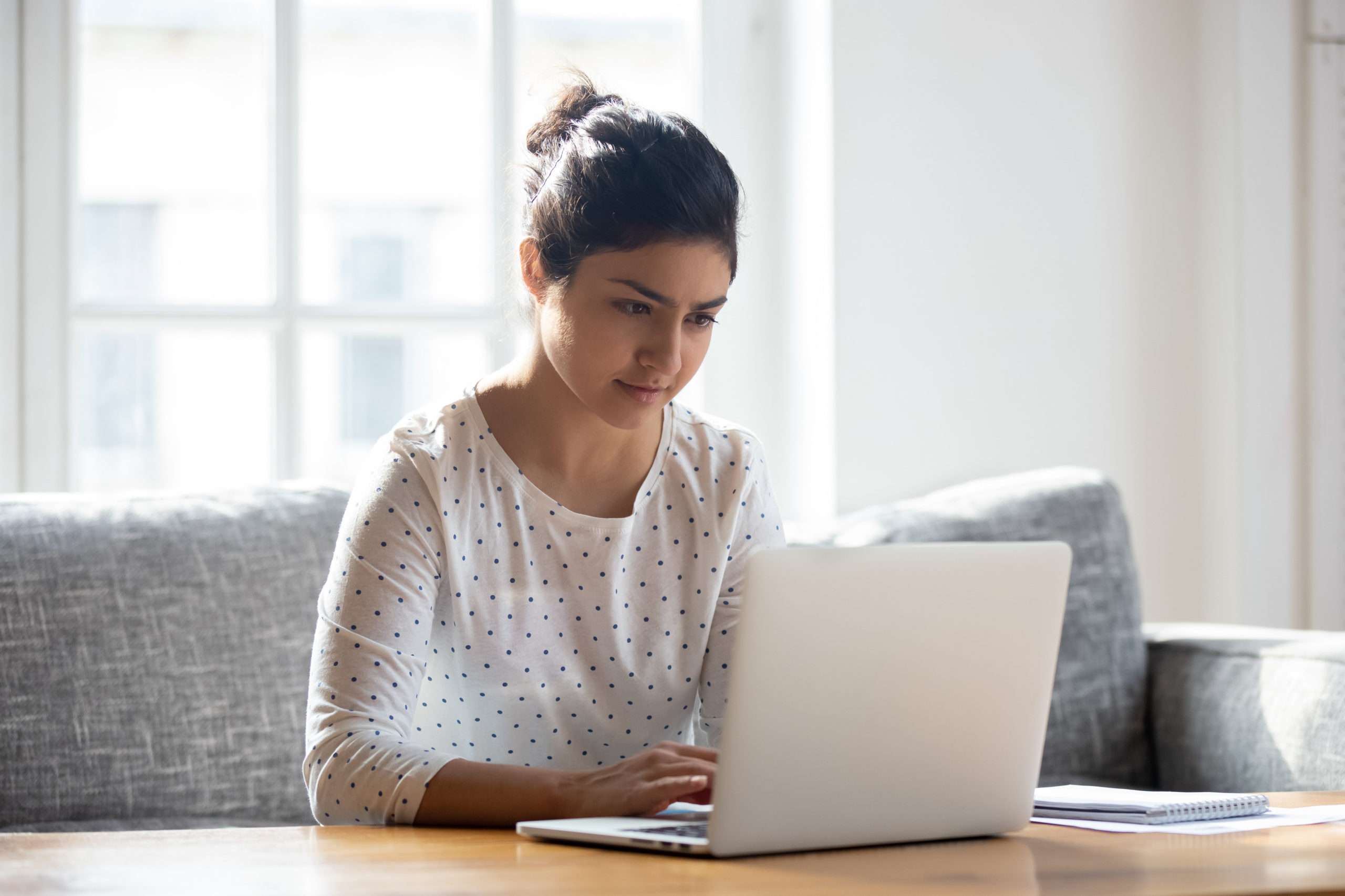 woman using laptop at home, looking at screen