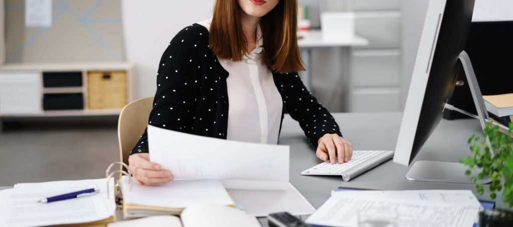 businesswoman sitting at desk checking documents