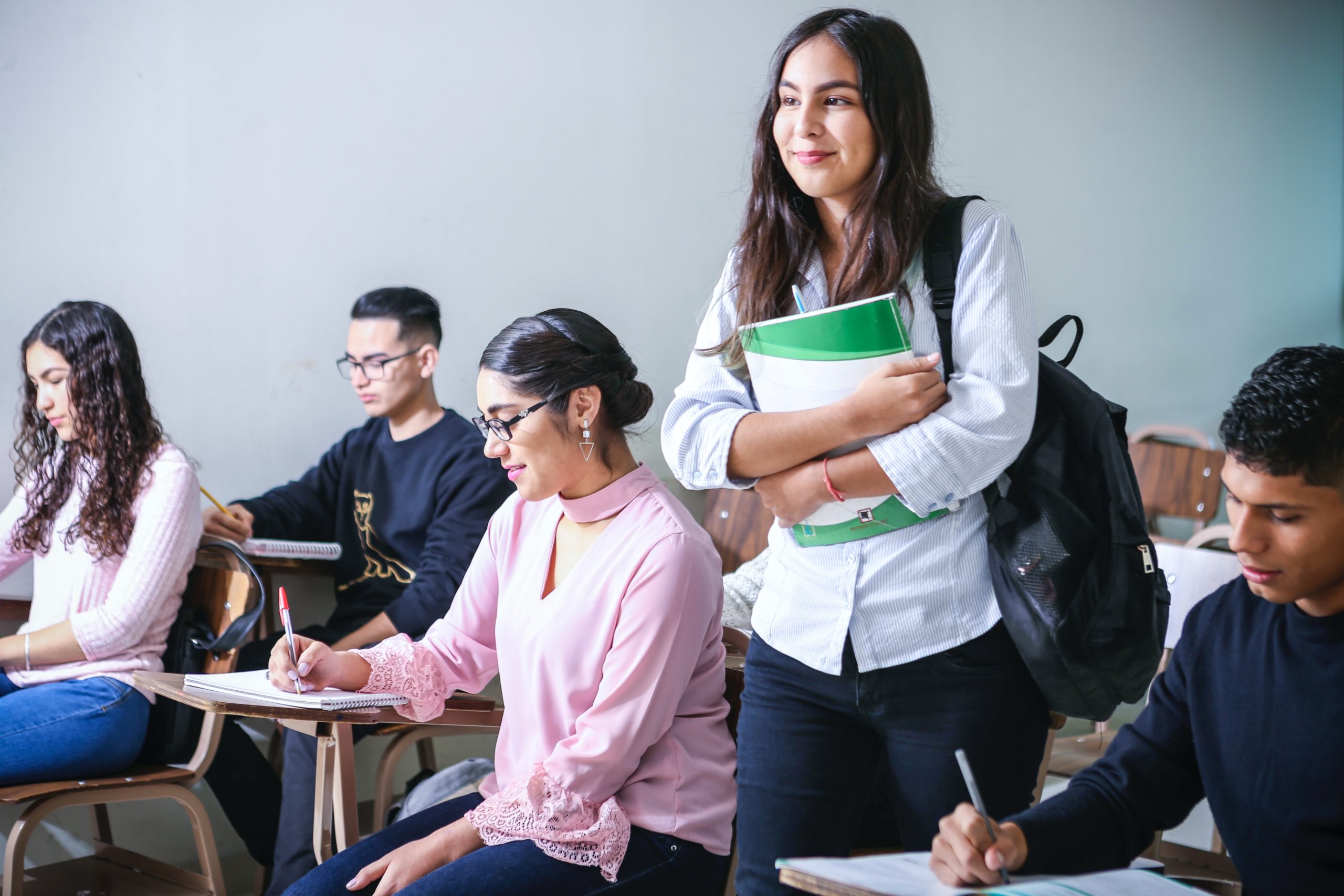 High school student holding textbooks in classroom