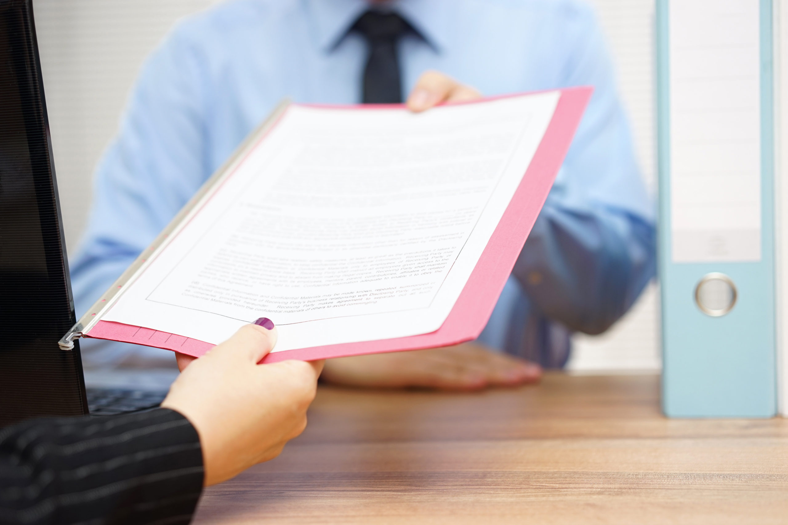 woman handing paper scholarship application to man