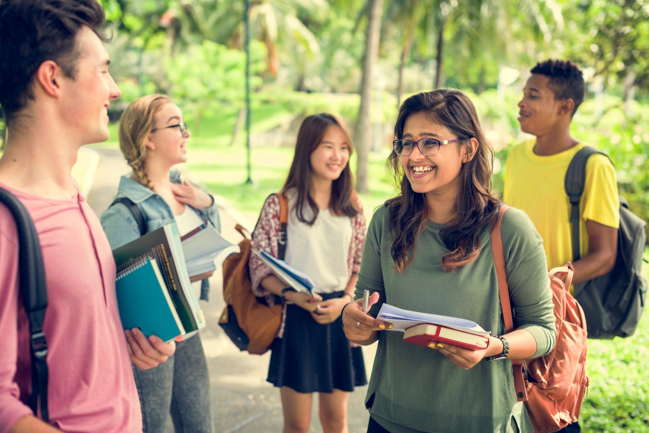 Diverse group of college students holding books outdoors