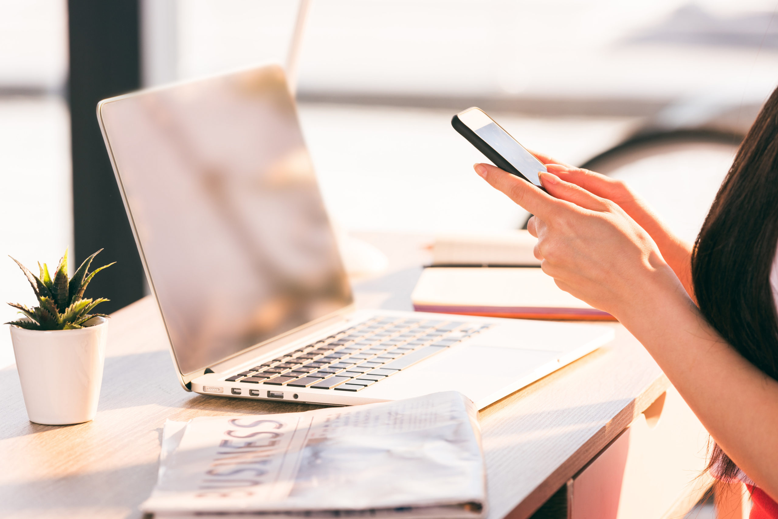 cropped view of woman working with smartphone laptop at workplace in office. filling out scholarship application.