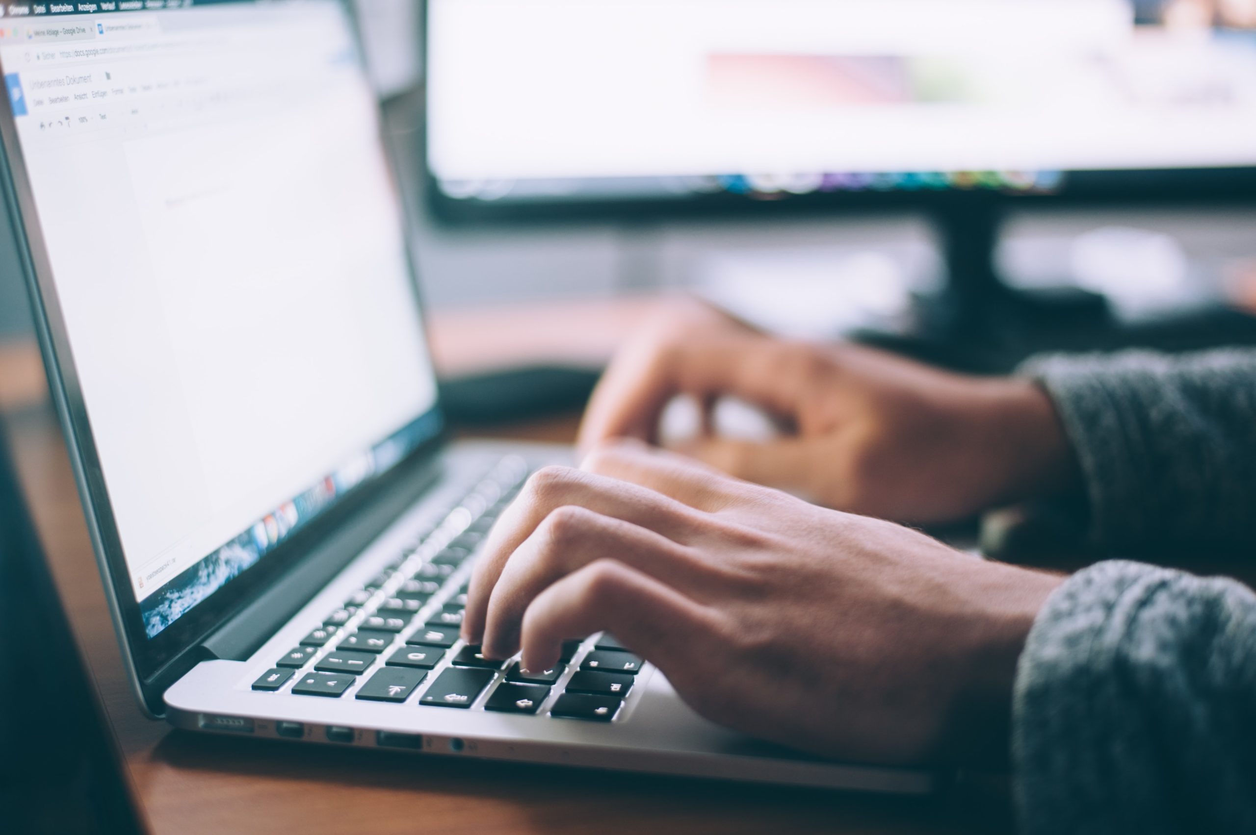 student typing essay on laptop computer