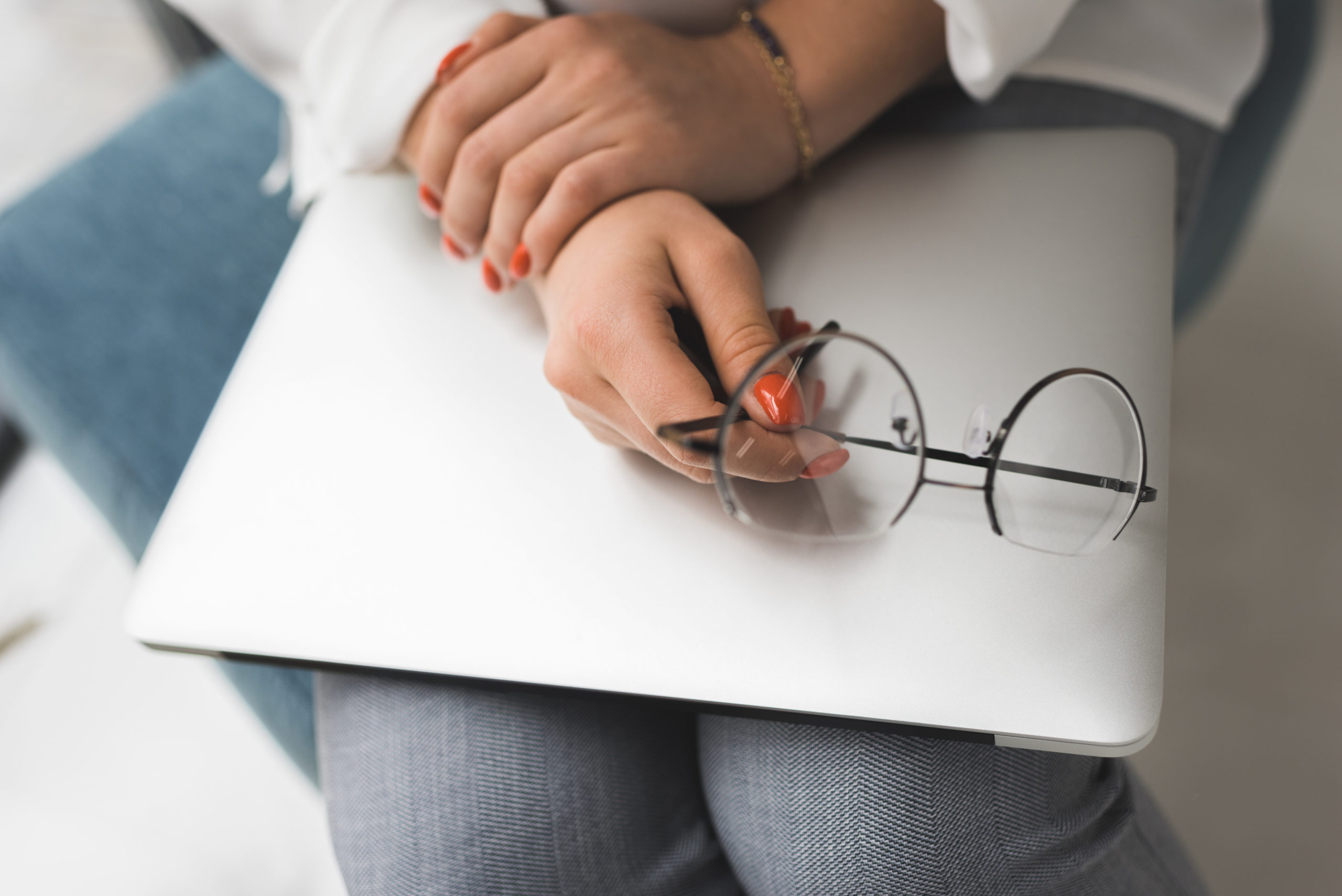 female hands with laptop and eyeglasses in office