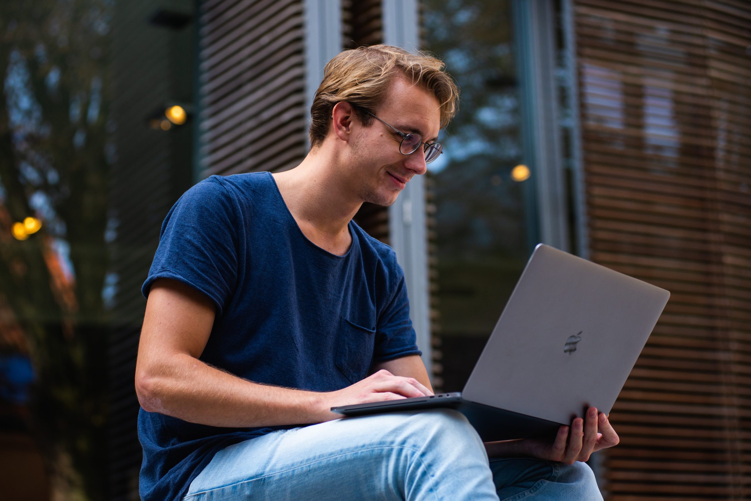 young man sits smiling at laptop